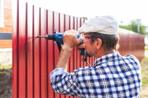 man installing a metal fence