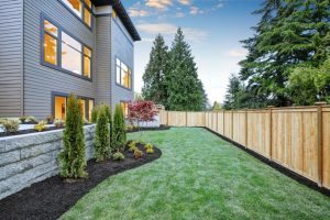 Nice backyard landscape with well kept lawn, flower beds and wooden fence.