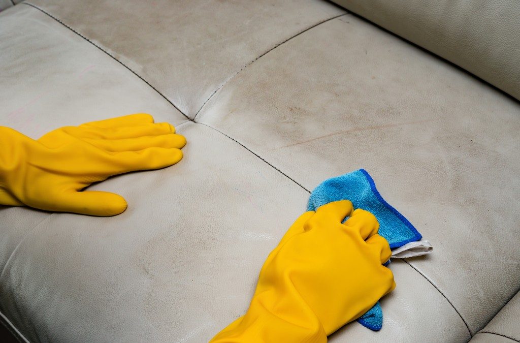 yellow gloves cleaning furniture