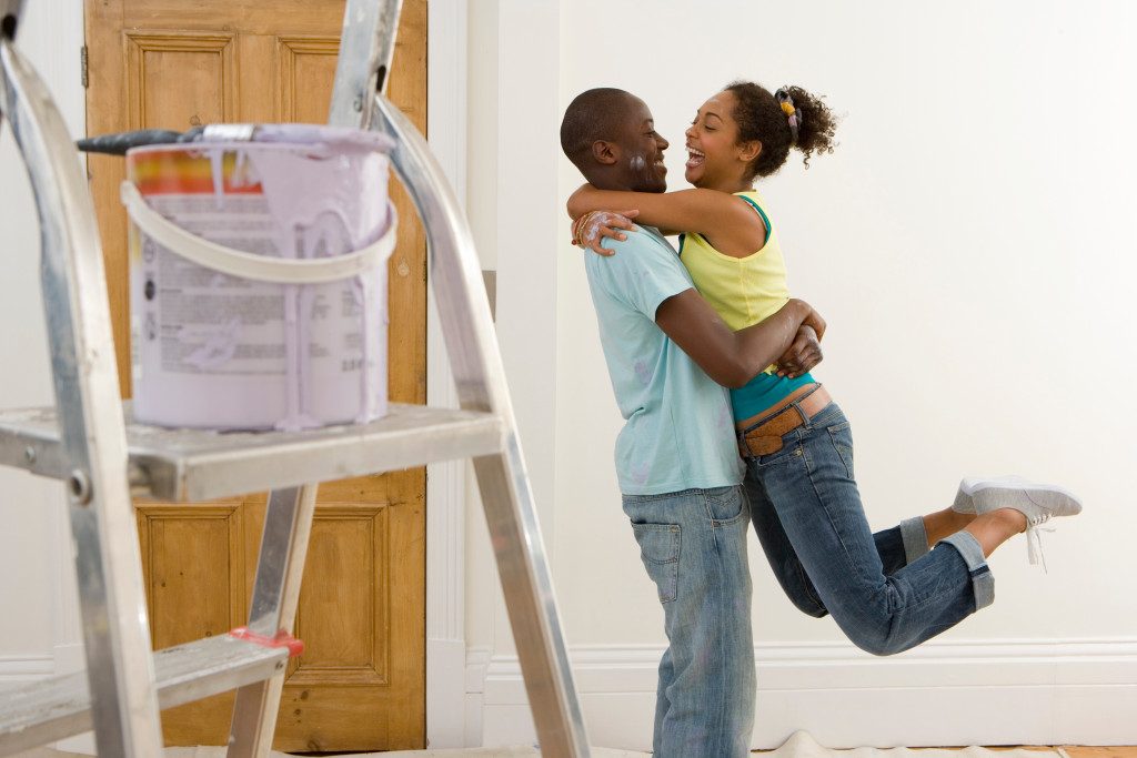 Young couple celebrating after painting a room in their home.