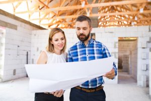 A couple looking at blueprints on a home construction site