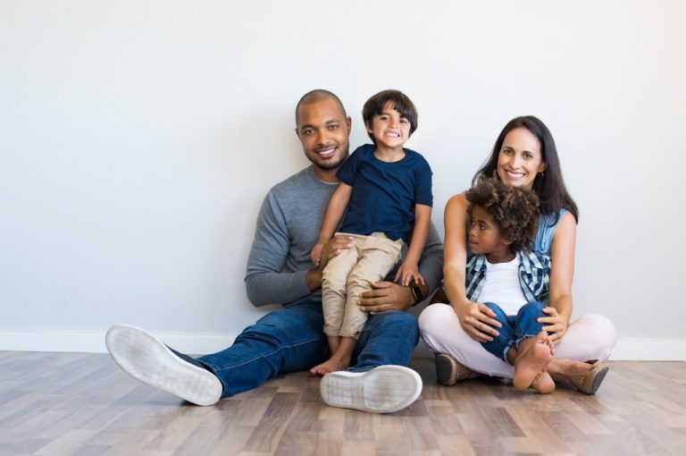 Smiling couple sitting with two sons and looking at camera.