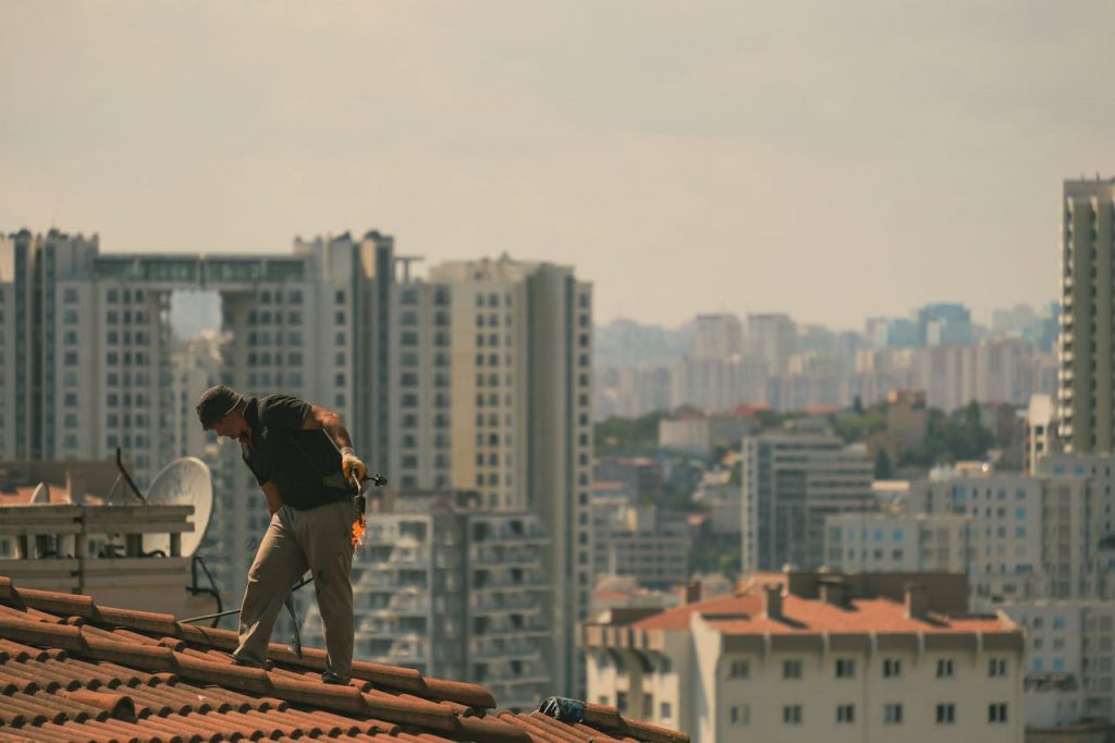 Worker inspecting roof tiles on a residential house to identify potential leaks
