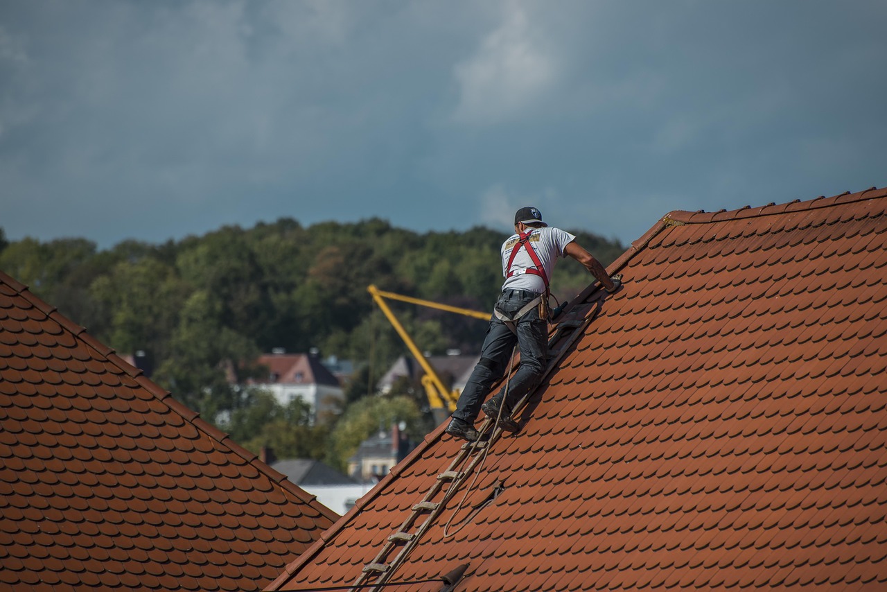 Roofer with safety harness inspecting a steep tile roof during a professional roof inspection for leaks and structural issues