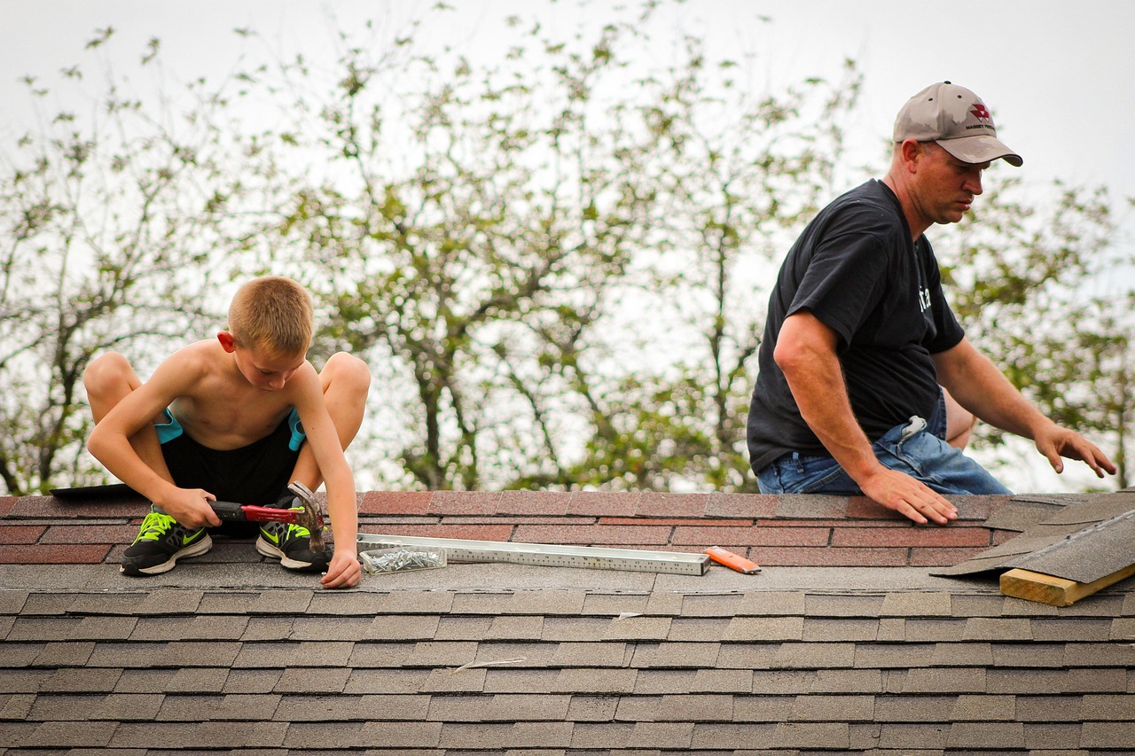Homeowners inspecting damaged asphalt shingles to locate roof leak issues such as cracks, missing shingles, and nail pops.
